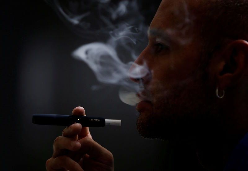 © Reuters. FILE PHOTO: A man poses for a photograph while using a Philip Morris iQOS smoking device in Bogota