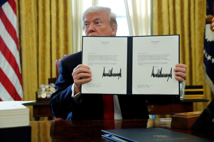 © Reuters. U.S. President Donald Trump signs tax overhaul legislation into law in the Oval Office at the White House in Washington