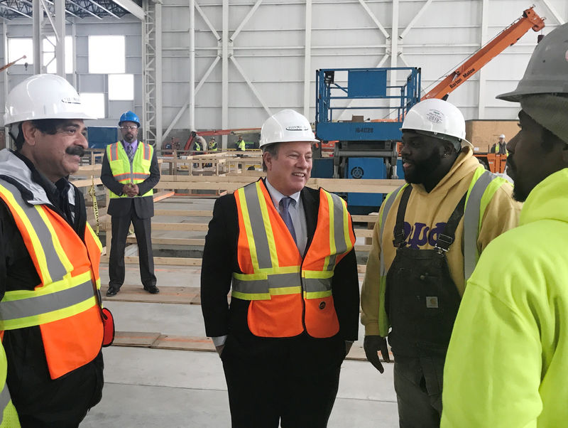 © Reuters. Shahid Khan, owner of auto supplier Flex-N-Gate, and Detroit Mayor Mike Duggan speak with plumber Aaron Barners during a tour of Flex-N-GateÕs new auto parts factory, in Detroit