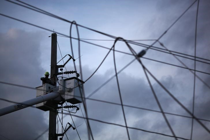 © Reuters. A worker of Puerto Rico's Electric Power Authority (PREPA) repairs part of the electrical grid after Hurricane Maria hit the area in September, in Manati