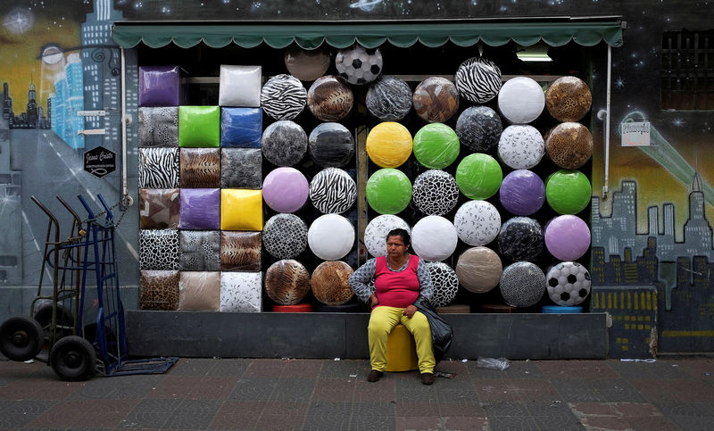 © Reuters. FILE PHOTO: A woman sits in front of a shop selling stools after buying one in the Bras neighborhood of Sao Paulo