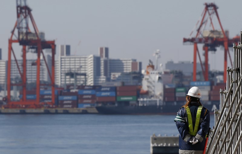 © Reuters. A worker walks near a container area at a port in Toky