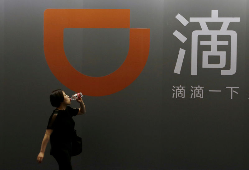 © Reuters. FILE PHOTO: A woman walks past Didi Chuxing's booth at the GMIC in Beijing