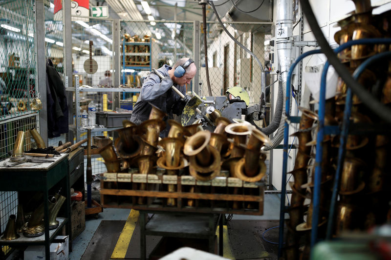 © Reuters. A worker forms the bells of saxophones at the Henri Selmer wind instruments factory in Mantes-la-Ville near Paris