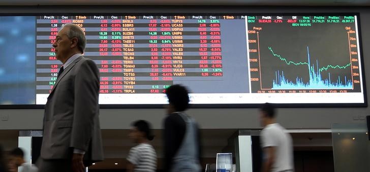 © Reuters. Pessoas passam por tela com índices do mercado na Bolsa de Valores de São Paulo, em São Paulo