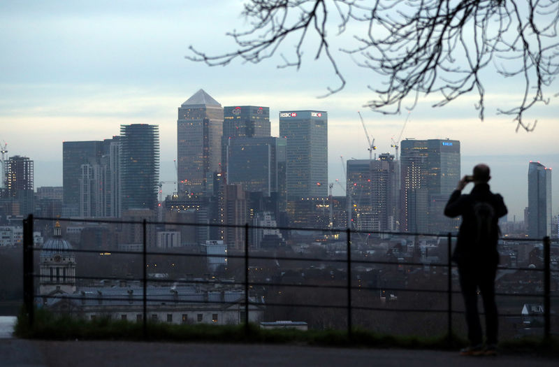 © Reuters. A man takes a photograph of the Canary Wharf financial district from Greenwich Park in London