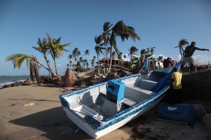 © Reuters. People recover items from a boat they found washed up on the shore, after Hurricane Maria hit the island in September, in Loiza