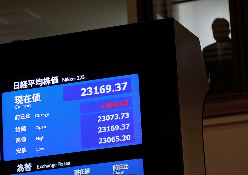 © Reuters. A man is seen behind an electronic board displaying the Nikkei average after the ceremony which kicks off the first day of trading in 2018 at the Tokyo Stock Exchange in Tokyo