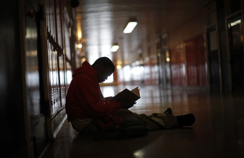 © Reuters. A student at Leo Catholic High School sits in the hallway as he looks through a text book in Chicago, Illinois