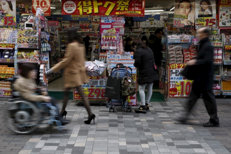 © Reuters. A woman with a baby buggy looks at items outside a discount store at a shopping district in Tokyo