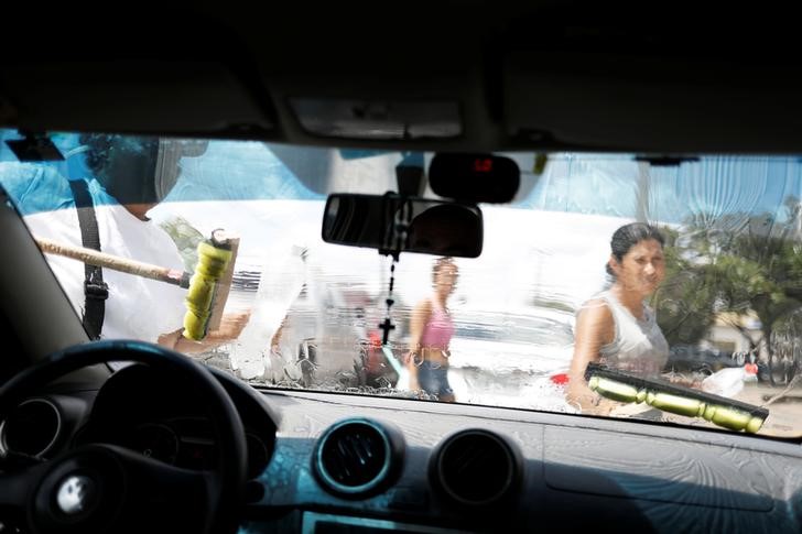 © Reuters. Venezuelanos limpam janela de carros em Boa Vista