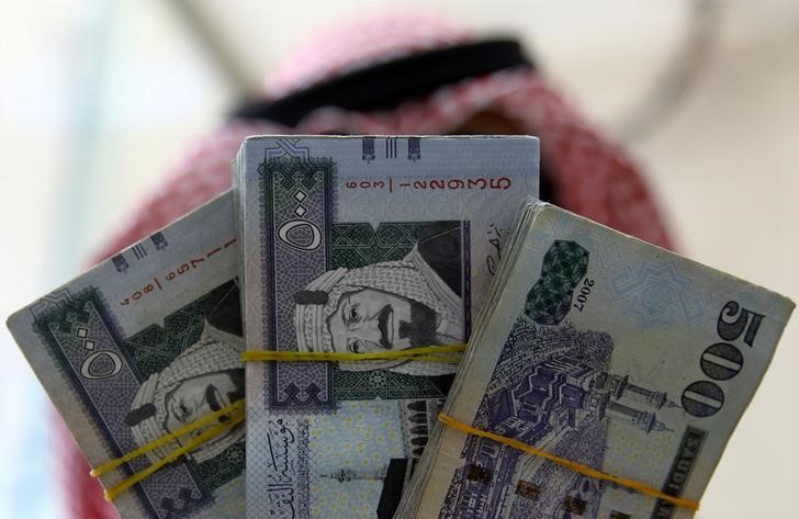 © Reuters. FILE PHOTO: A Saudi money changer displays Saudi Riyal banknotes at a currency exchange shop in Riyadh