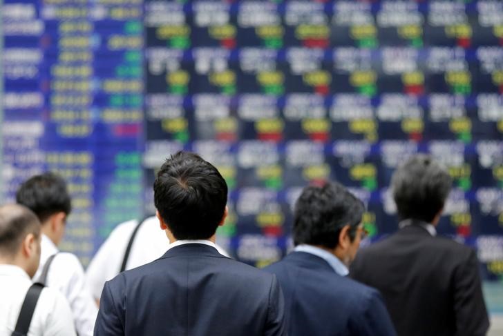 © Reuters. People walk past an electronic stock quotation board outside a brokerage in Tokyo