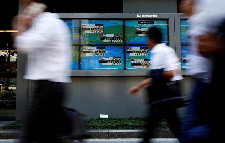© Reuters. People walk past an electronic board showing Japan's Nikkei average outside a brokerage at a business district in Tokyo