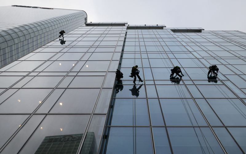 © Reuters. Workers clean the windows on the KPMG building in London's Canary Wharf financial district in London