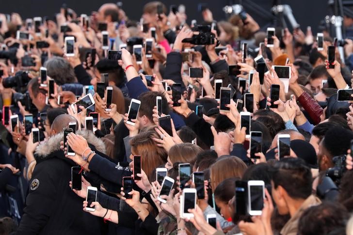 © Reuters. People use their smartphone to take photos on the Champs Elysees avenue during a public event in Paris