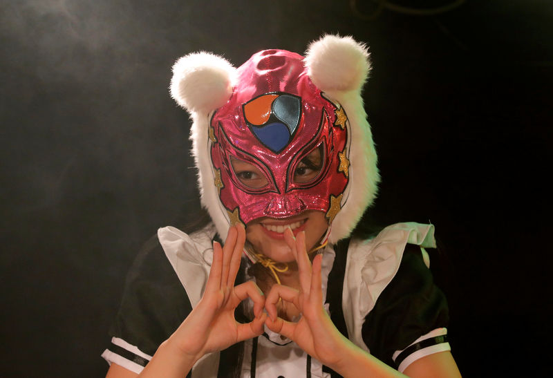 © Reuters. A member of JapanÕs idol group "Virtual Currency Girls" wearing a mask featuring the NEM cryptocurrency logo poses after performing on their debut stage in Tokyo