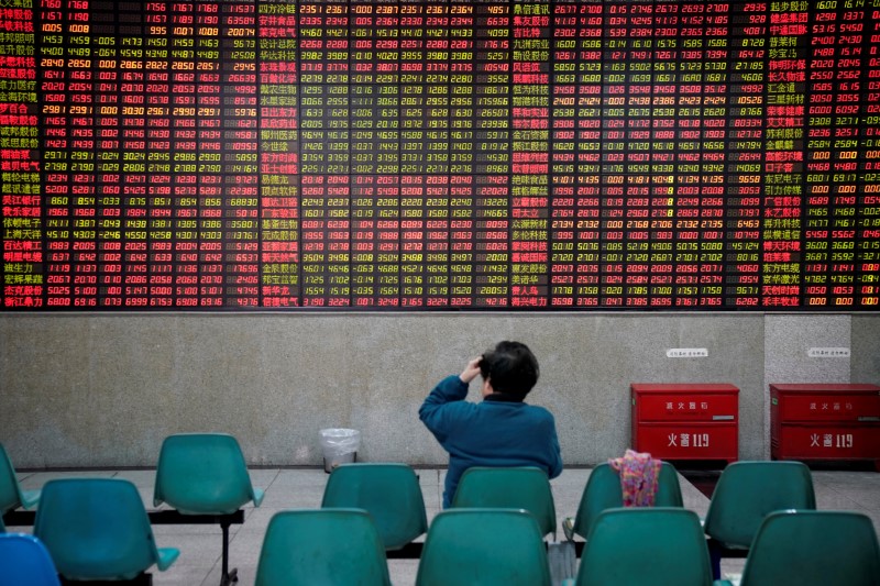 © Reuters. An investor looks at an electronic board showing stock information at a brokerage house in Shanghai