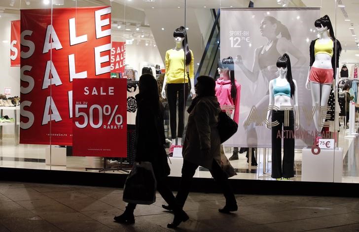 © Reuters. FILE PHOTO - Pedestrians walk past a store window advertising up to 50 percent discount during winter sales in Berlin