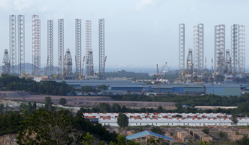 © Reuters. Oil rigs line the waters along a row of shipyards northwest of Waterfront City on Batam island