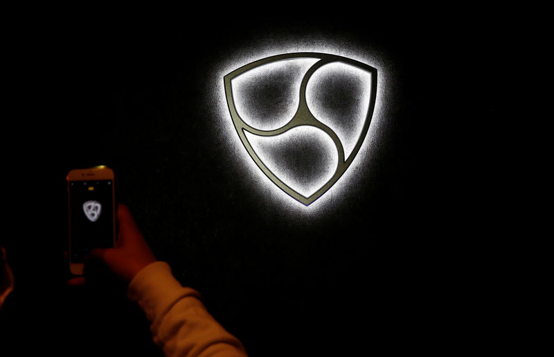 © Reuters. A man takes a picture of a decoration implying the symbol of NEM coin which is hung on a wall at 'nem bar', where customers can pay with NEM coins, in Tokyo