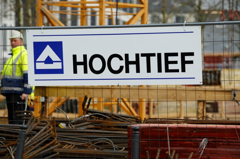© Reuters. A worker of German construction company Hochtief stands next to the company's logo in Essen