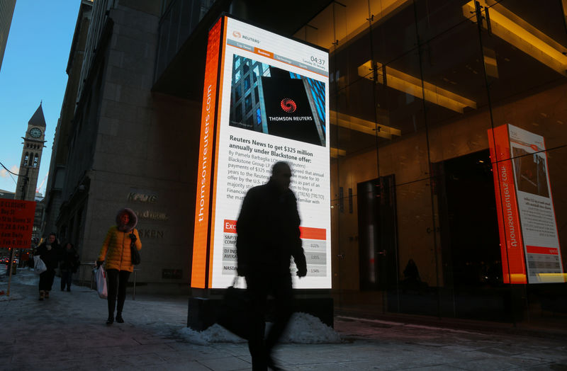 © Reuters. A man passes a digital billboard showing news of talks between Thomson Reuters and Blackstone in Toronto