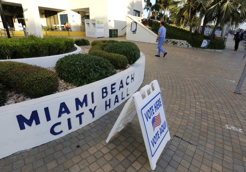 © Reuters. A voter walks to a poll with no line as it opened for the U.S. presidential election in Miami Beach