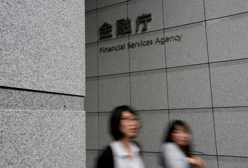 © Reuters. FILE PHOTO: Women walk under a sign of Japan's Financial Services Agency in Tokyo, Japan