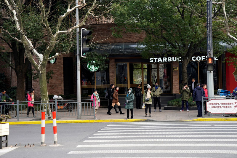 © Reuters. Pessoas passam por loja do Starbucks em Xangai após veículo em chamas ter invadido a calçada