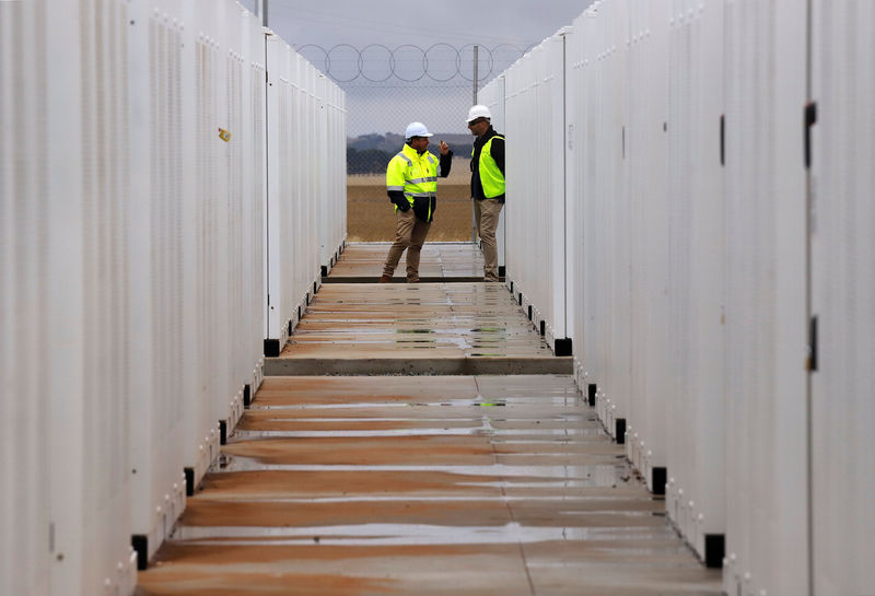© Reuters. FILE PHOTO: Workers stand inside the compound for the Hornsdale Power Reserve, featuring the world's largest lithium ion battery made by Tesla, during the official launch near the South Australian town of Jamestown