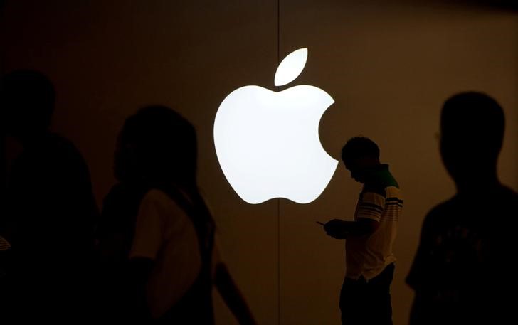 © Reuters. FILE PHOTO: A man looks at the screen of his mobile phone in front of an Apple logo outside its store in Shanghai