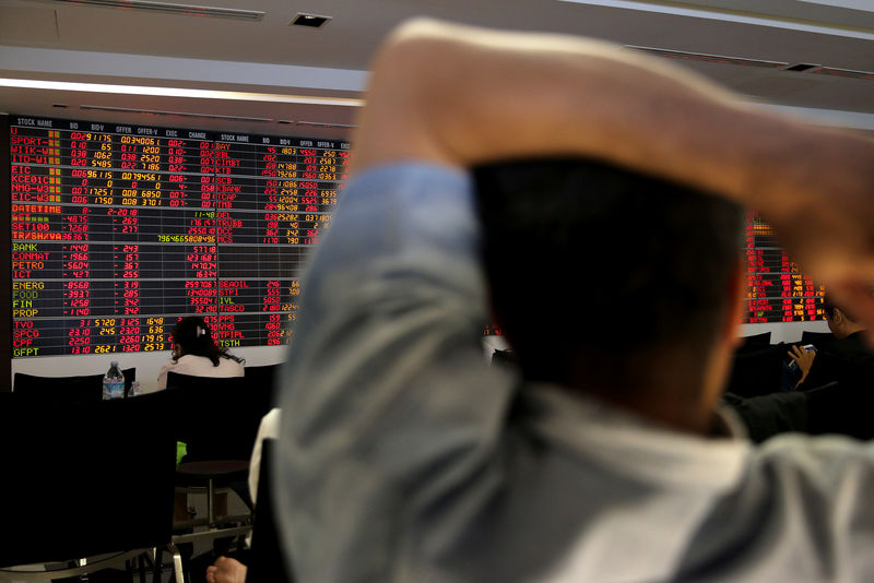 © Reuters. People monitor a stock index board at a bank in Bangkok