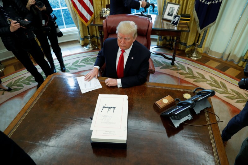 © Reuters. U.S. President Donald Trump signs tax overhaul legislation into law in the Oval Office at the White House in Washington