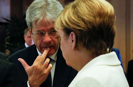© Reuters. Il premier Paolo Gentiloni (a sinistra) conversa con il cancelliere tedesco Angela Merkel in una foto d'archivio