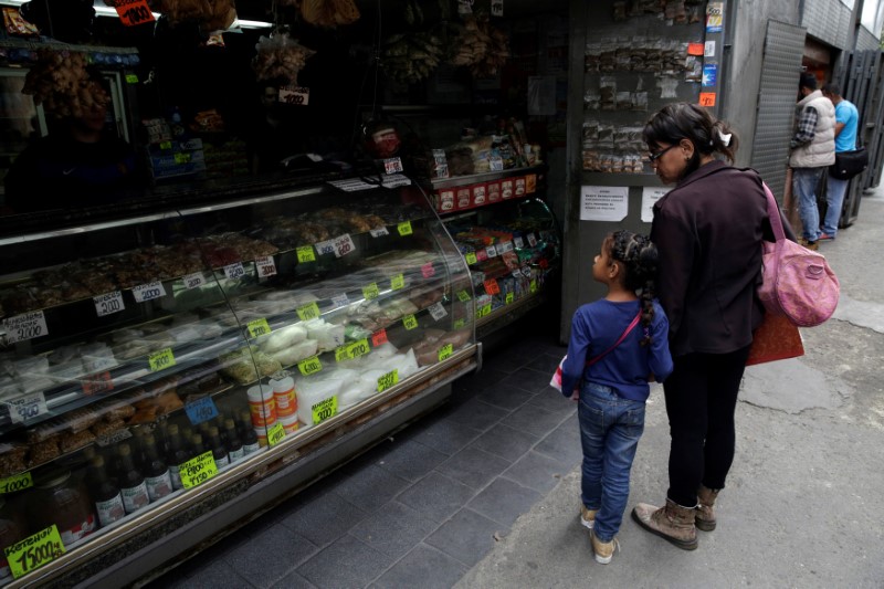 © Reuters. A woman and a child look at prices in a grocery store in downtown Caracas