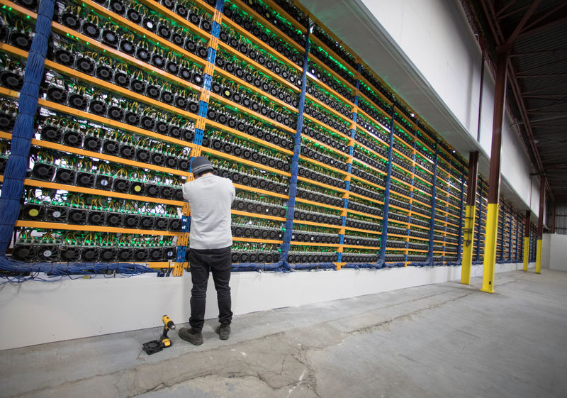 © Reuters. A worker checks the fans on miners at the cryptocurrency farming operation Bitfarms in Farnham, Quebec