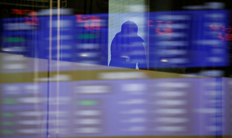 © Reuters. A visitor is seen as market prices are reflected in a glass window at the TSE in Tokyo