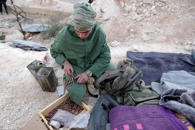 © Reuters. A Turkish-backed Free Syrian Army fighter prepares an ammunition belt in Eastern Afrin countryside