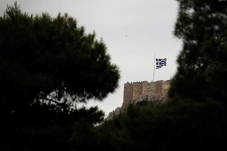 © Reuters. A Greek national flag waves over people visiting the Acropolis hill in Athens