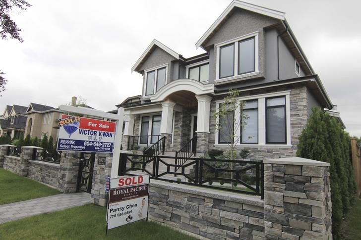 © Reuters. FILE PHOTO - Realtors' signs are hung outside a newly sold property in a Vancouver neighborhood