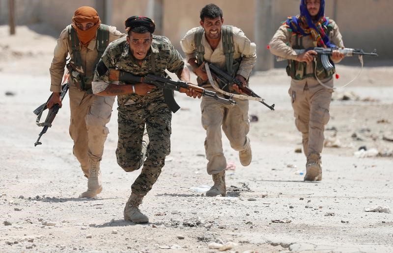 © Reuters. Imagen de archivo de combatientes kurdos de las milicias YPG cruzando una calle en la ciudad siria de Raqqa, Siria, en julio de 2017.