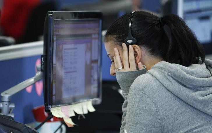 © Reuters. A worker on IG Index's trading floor puts her hand to her face as she speask on the phone while markets tumble, in London