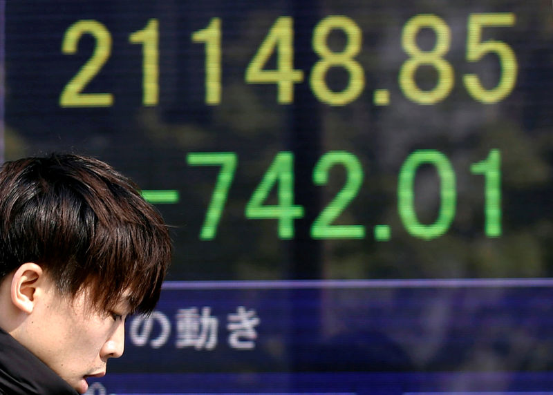 © Reuters. A man walks past an electronic board showing Japan's Nikkei average outside a brokerage in Tokyo