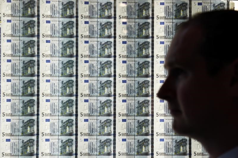© Reuters. A man is seen in front of a sheet of five Euro notes at the opening of the new Central Bank of Ireland offices in Dublin