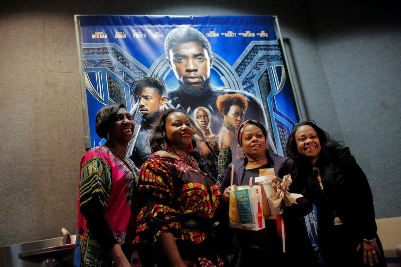 © Reuters. A group of women pose for a photo in front of a poster advertising the film "Black Panther" on its opening night of screenings at the AMC Magic Johnson Harlem 9 cinemas in Manhattan