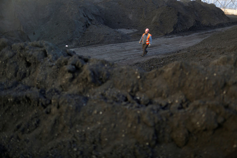 © Reuters. FILE PHOTO: Worker walks past coal piles at a coal coking plant in Yuncheng