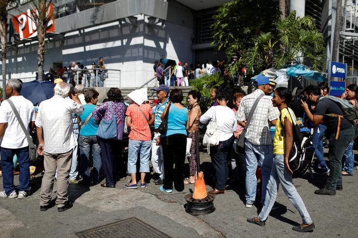 © Reuters. People wait in a queue to buy food, on a sidewalk outside a supermarket in Caracas