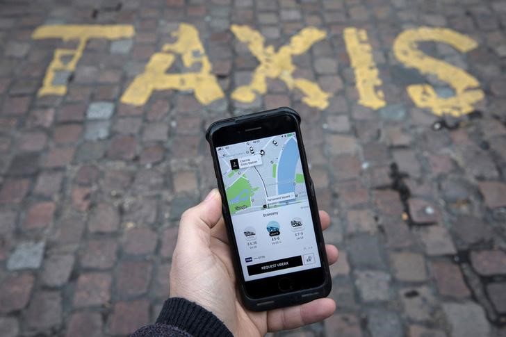 © Reuters. Foto ilustração de aplicativo da Uber em celular na frente de um ponto de táxi, em foto posada em Londres, Reino Unido