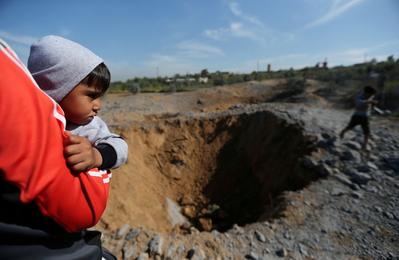 © Reuters. Palestinian boy is carried as he looks at the scene of an Israeli air strike, south of Gaza City